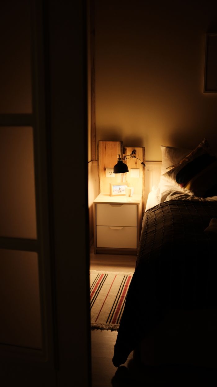 Warm and inviting bedroom scene featuring a lit nightstand, adding a cozy ambiance to the room.